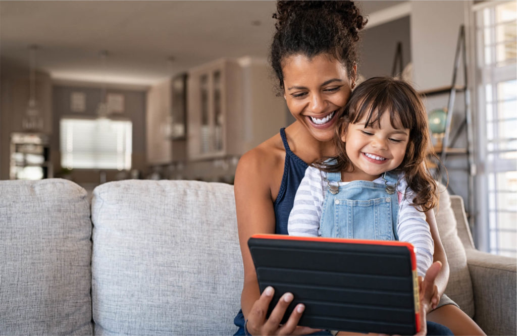 A woman and child stream content happily on a tablet
